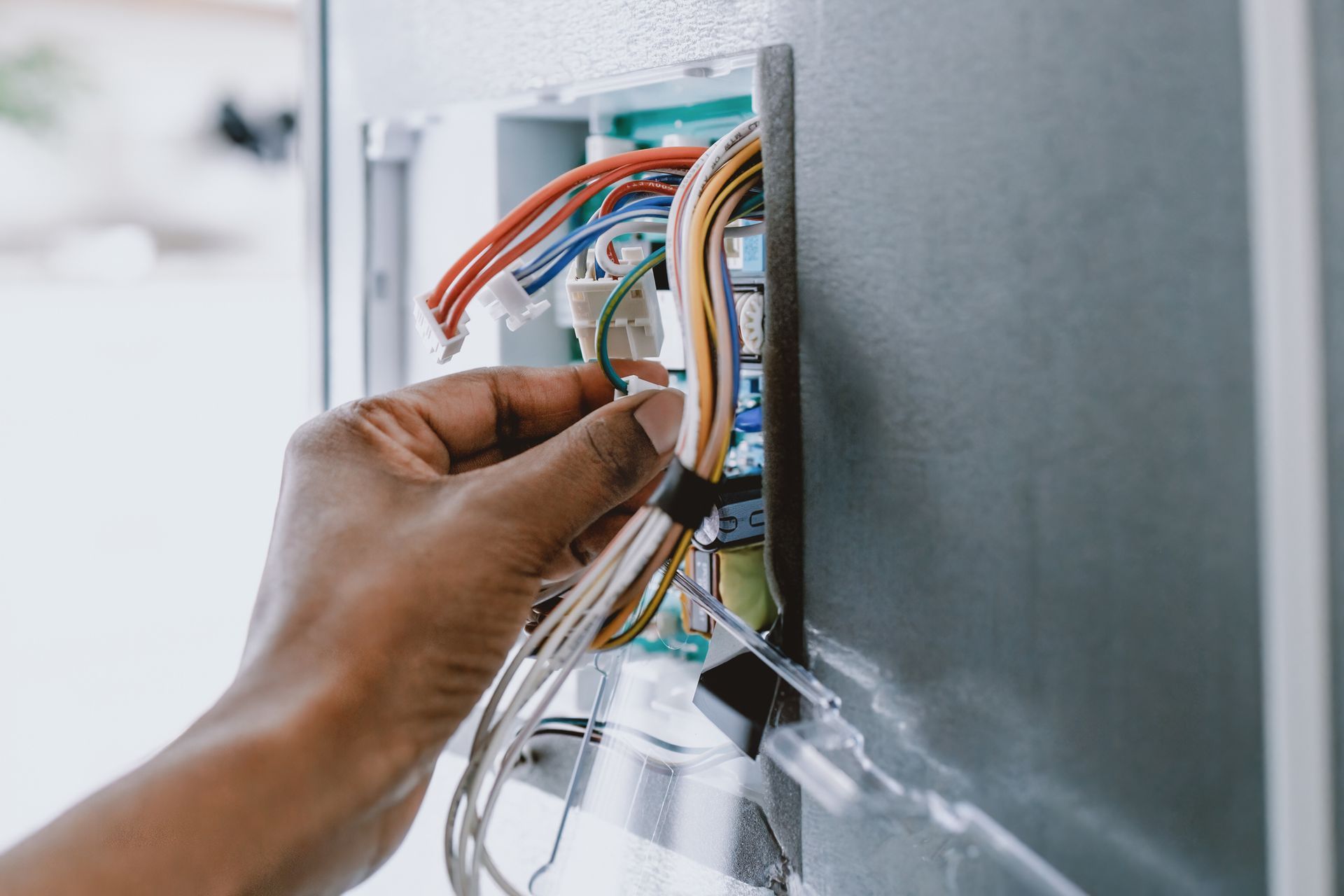A person is fixing a refrigerator with wires.