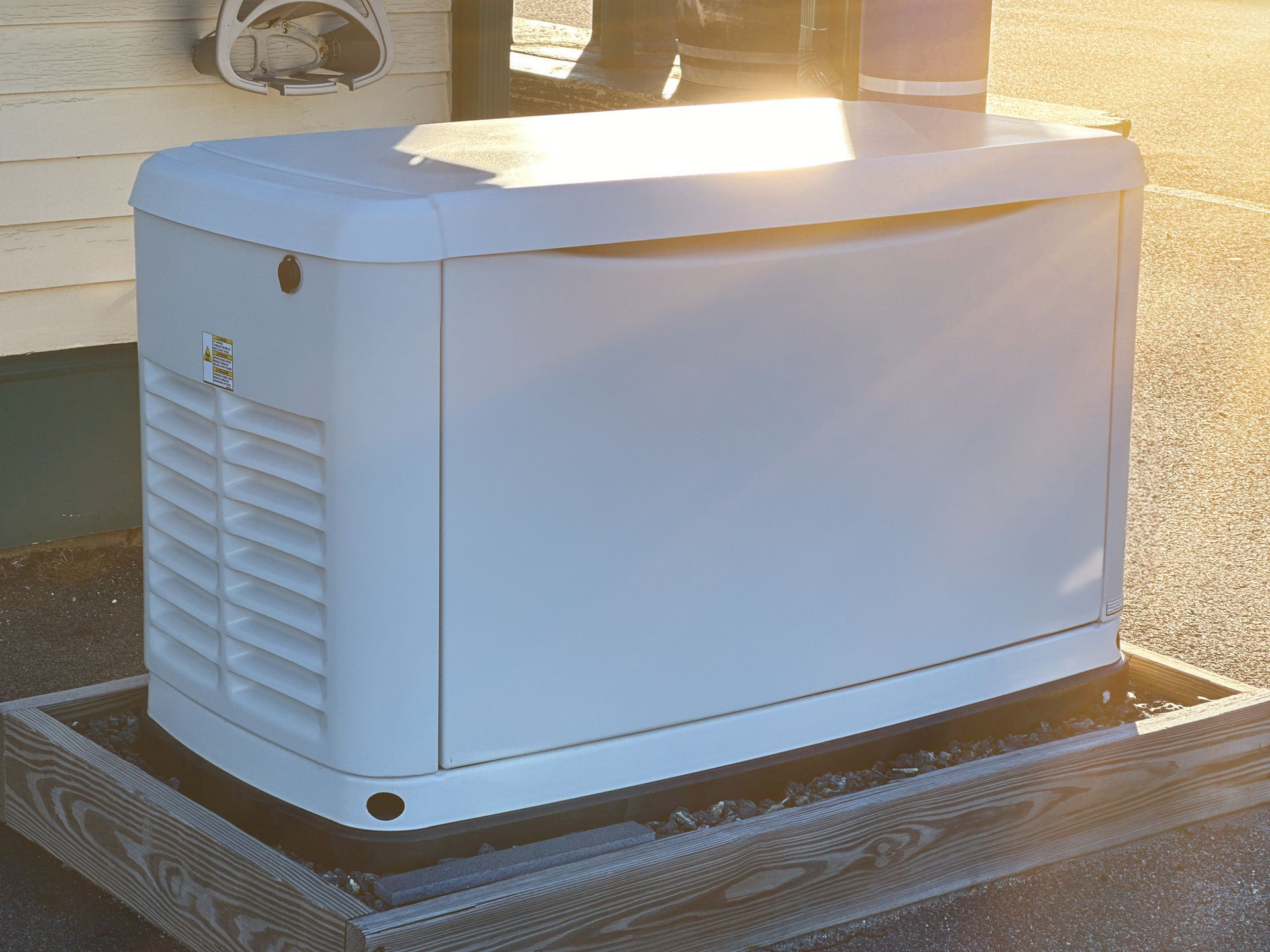 Backup generator on wooden platform beside building wall with vented sides visible.
