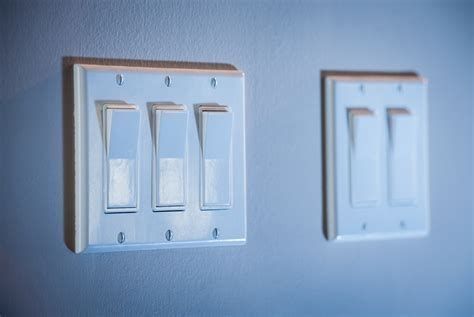 Two light switches are hanging on a wall.