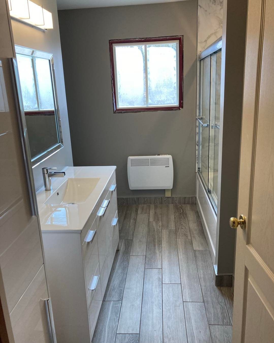 A bathroom with a sink , mirror and shower.