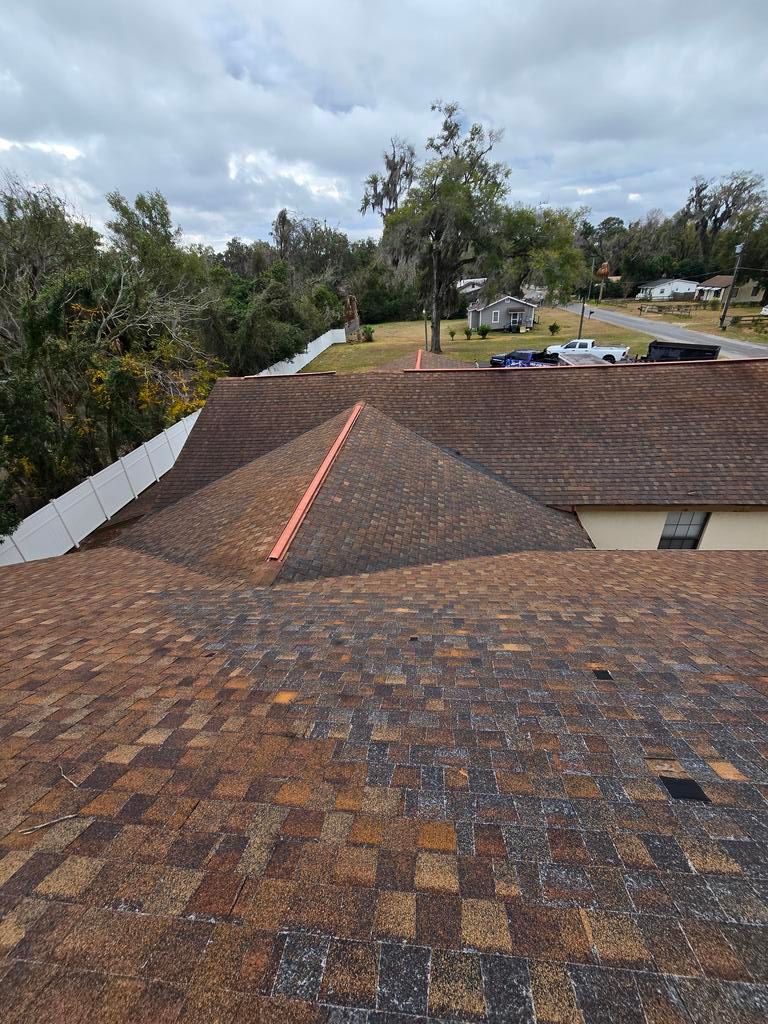 A brick house with a brown roof and black shutters