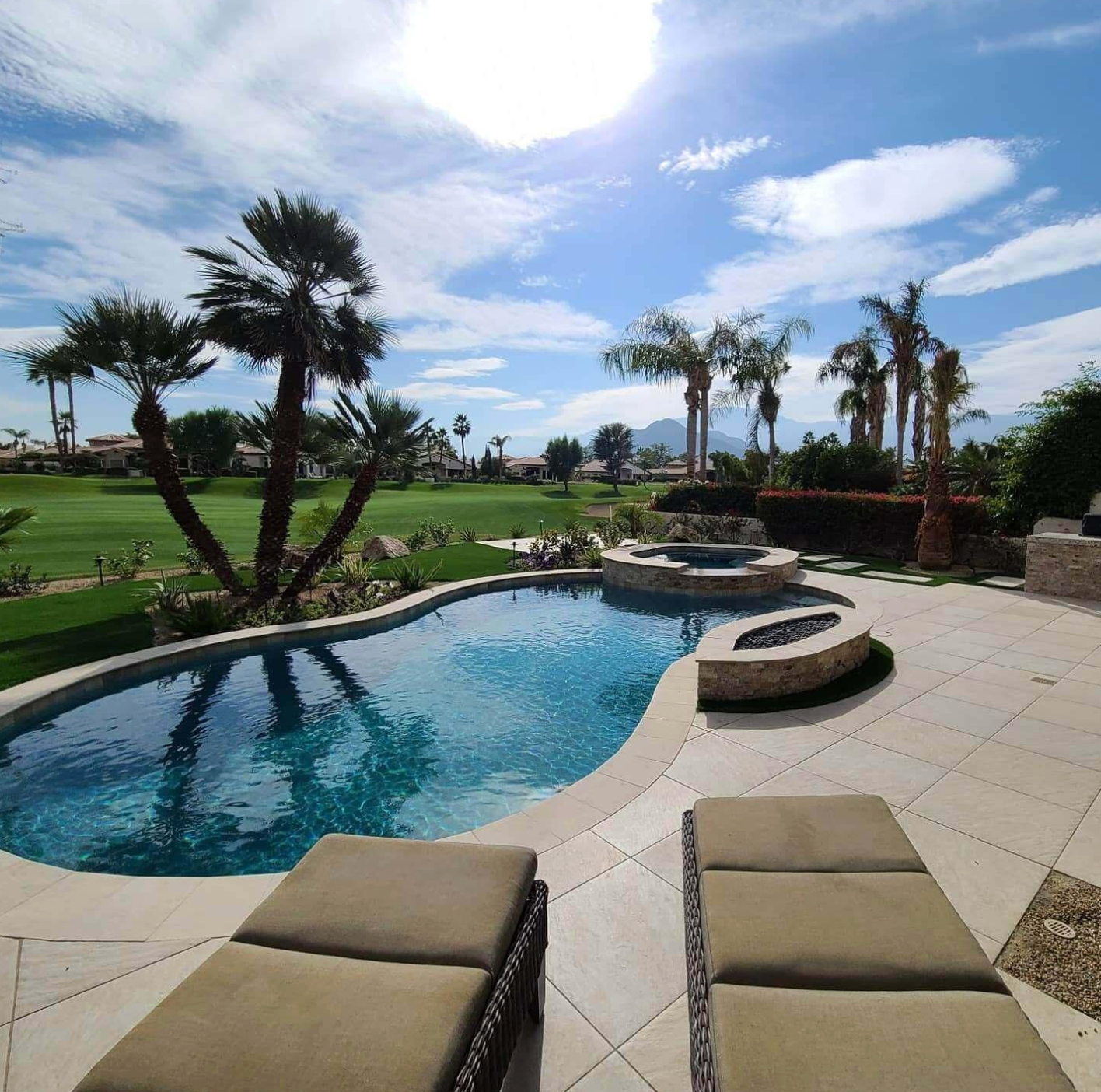 A large swimming pool surrounded by palm trees on a sunny day