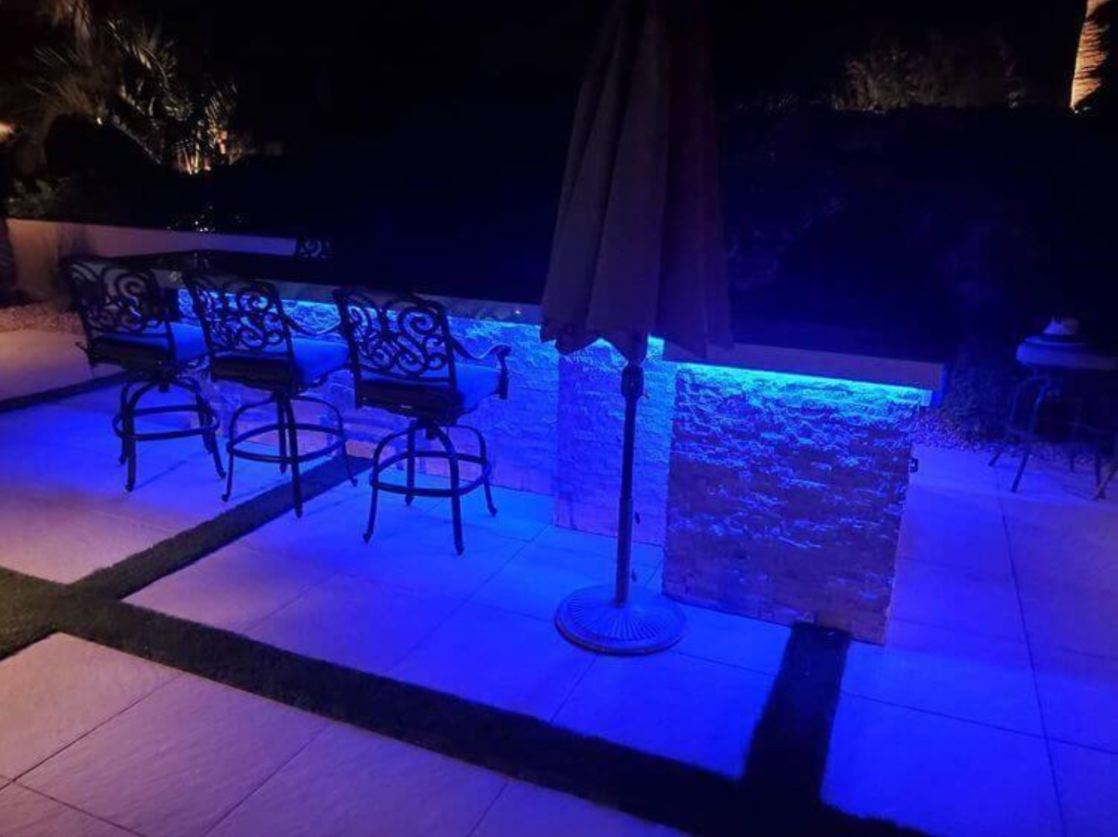 A patio with a table and chairs and blue lights.