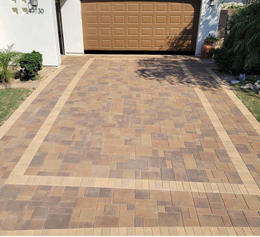 A brick driveway leads to a garage with a brown door
