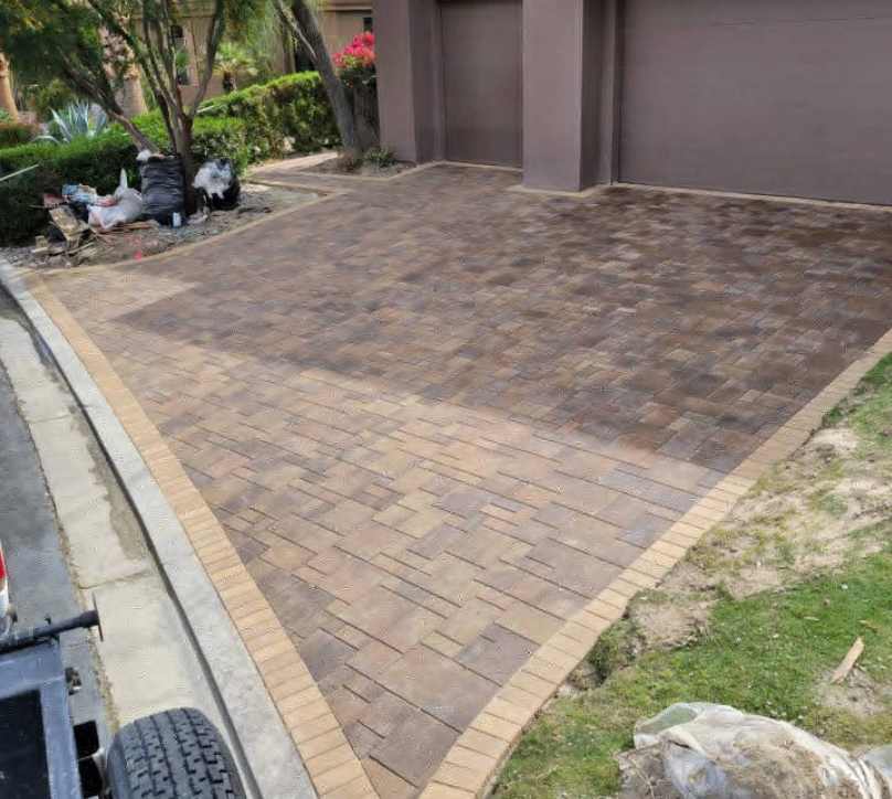 A brick driveway is being built in front of a house.