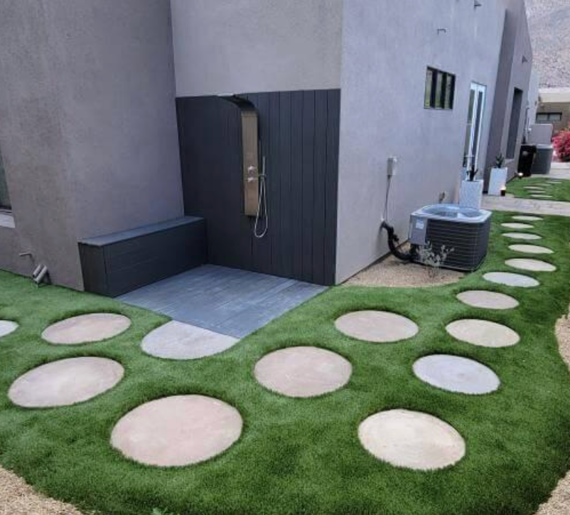 A house with a walkway and a shower in the backyard.