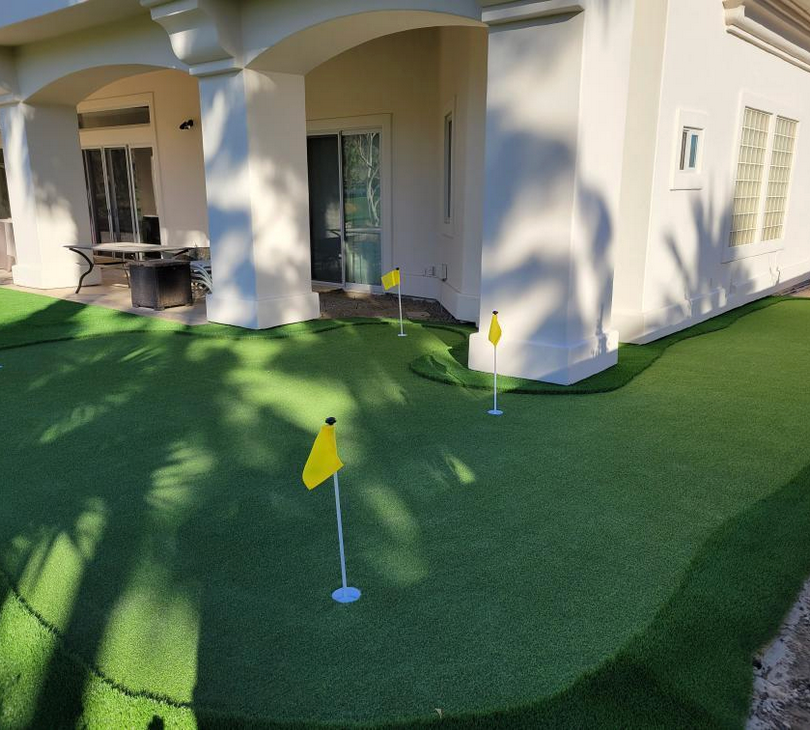 A white house with a putting green in front of it