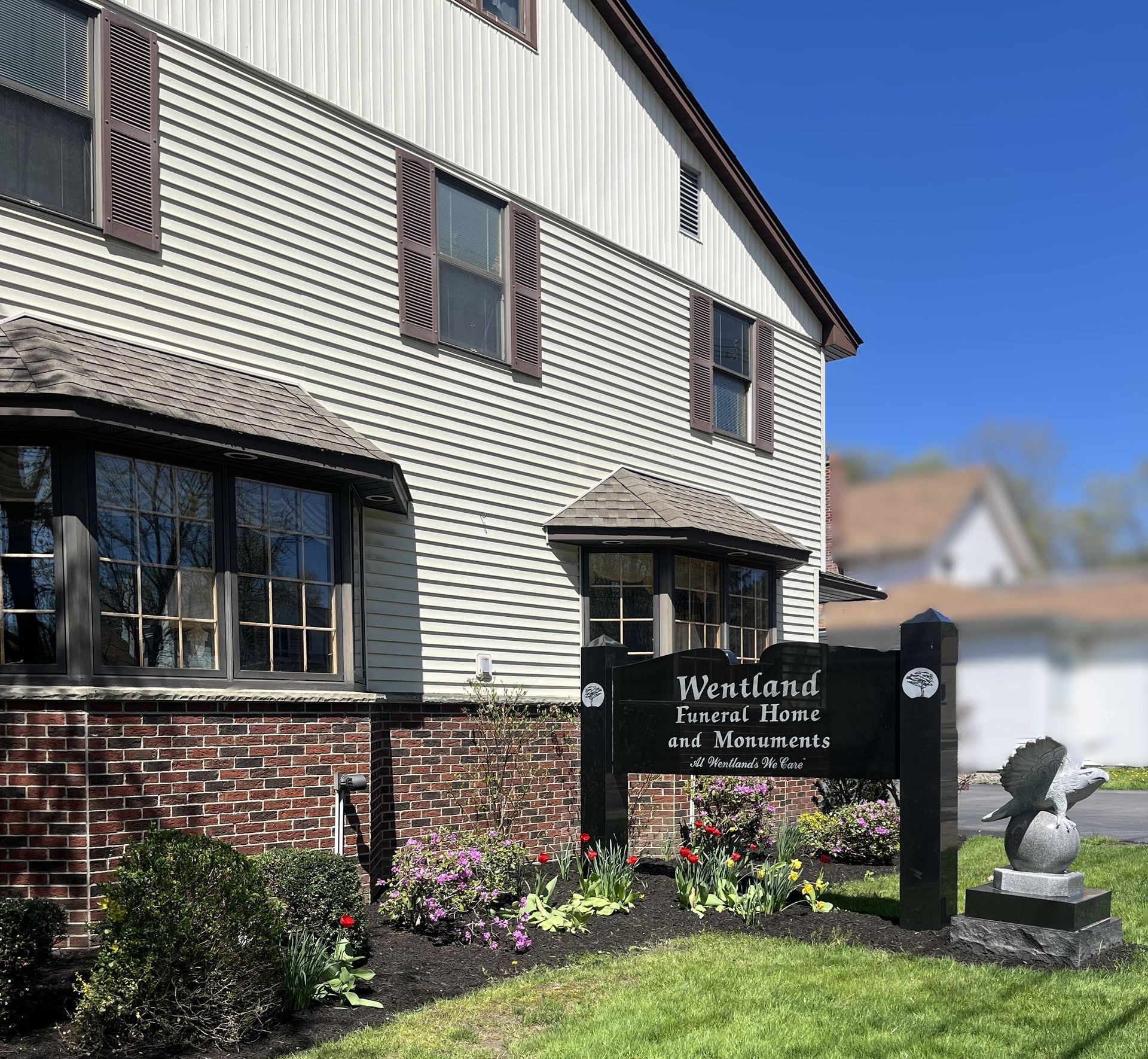 Wetland Medicine office sign outside a brick-and-sided building with flowers and a small stone sculpture