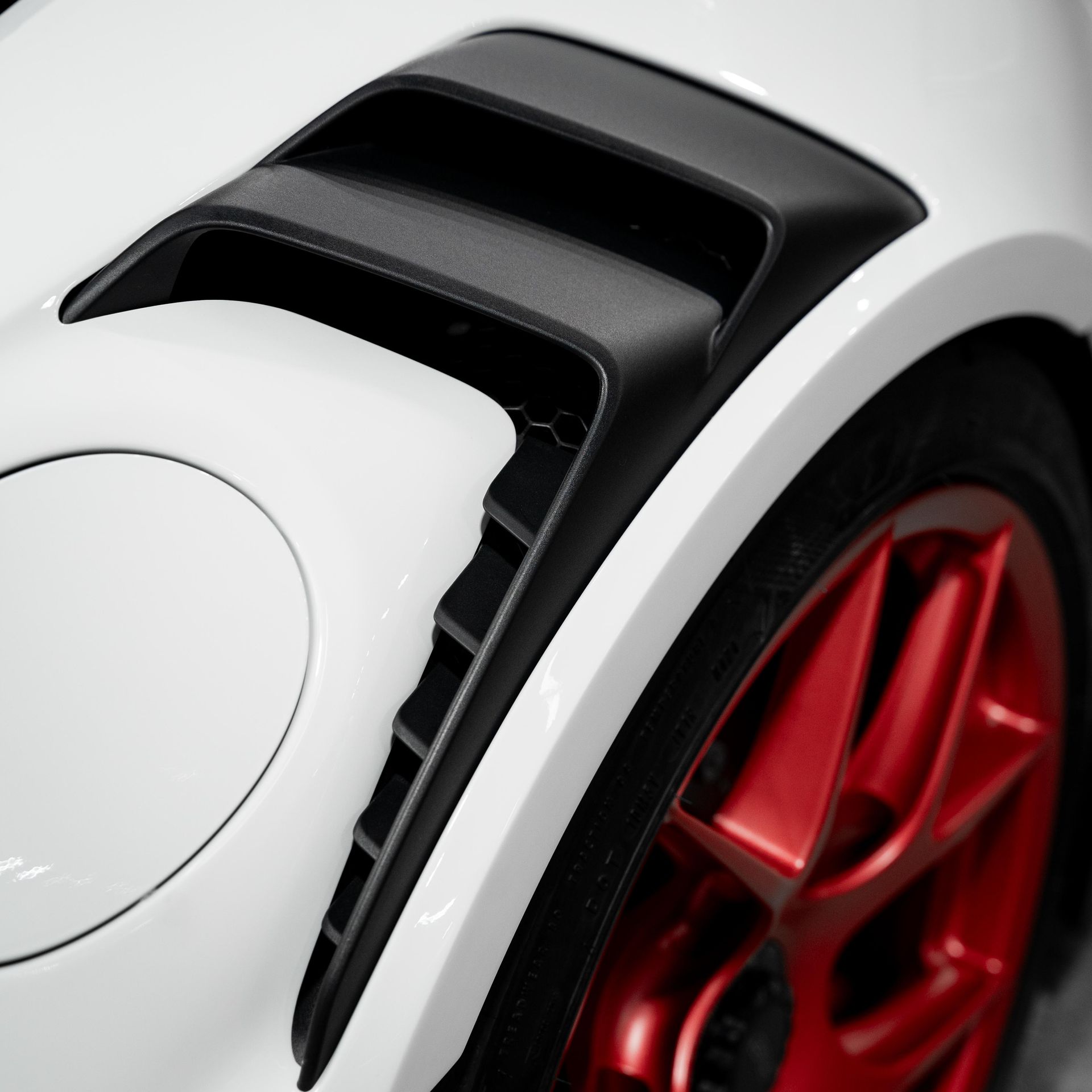 White car with black vents, red wheel. Close-up of the front wheel area of a car.