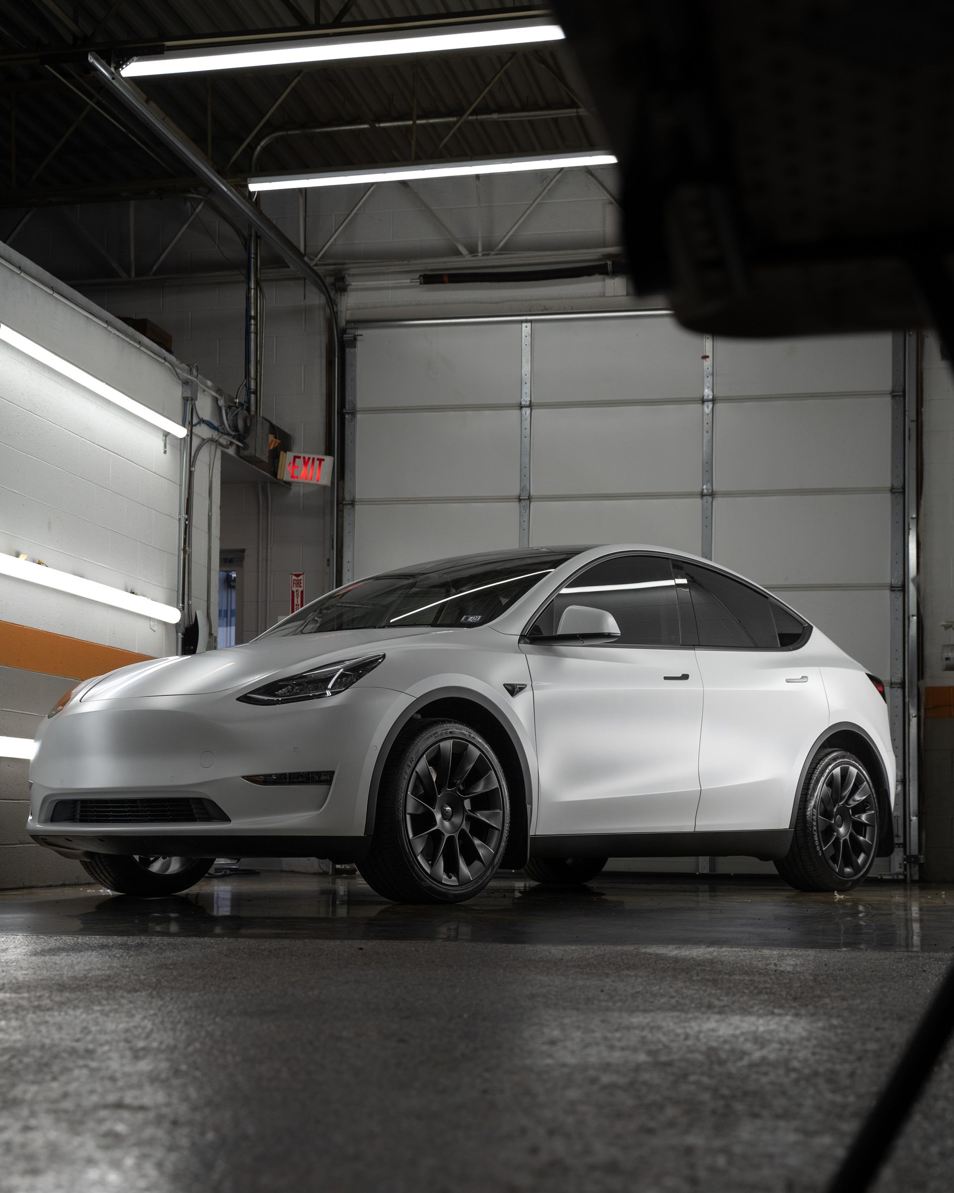 A white tesla model y is parked in a garage.