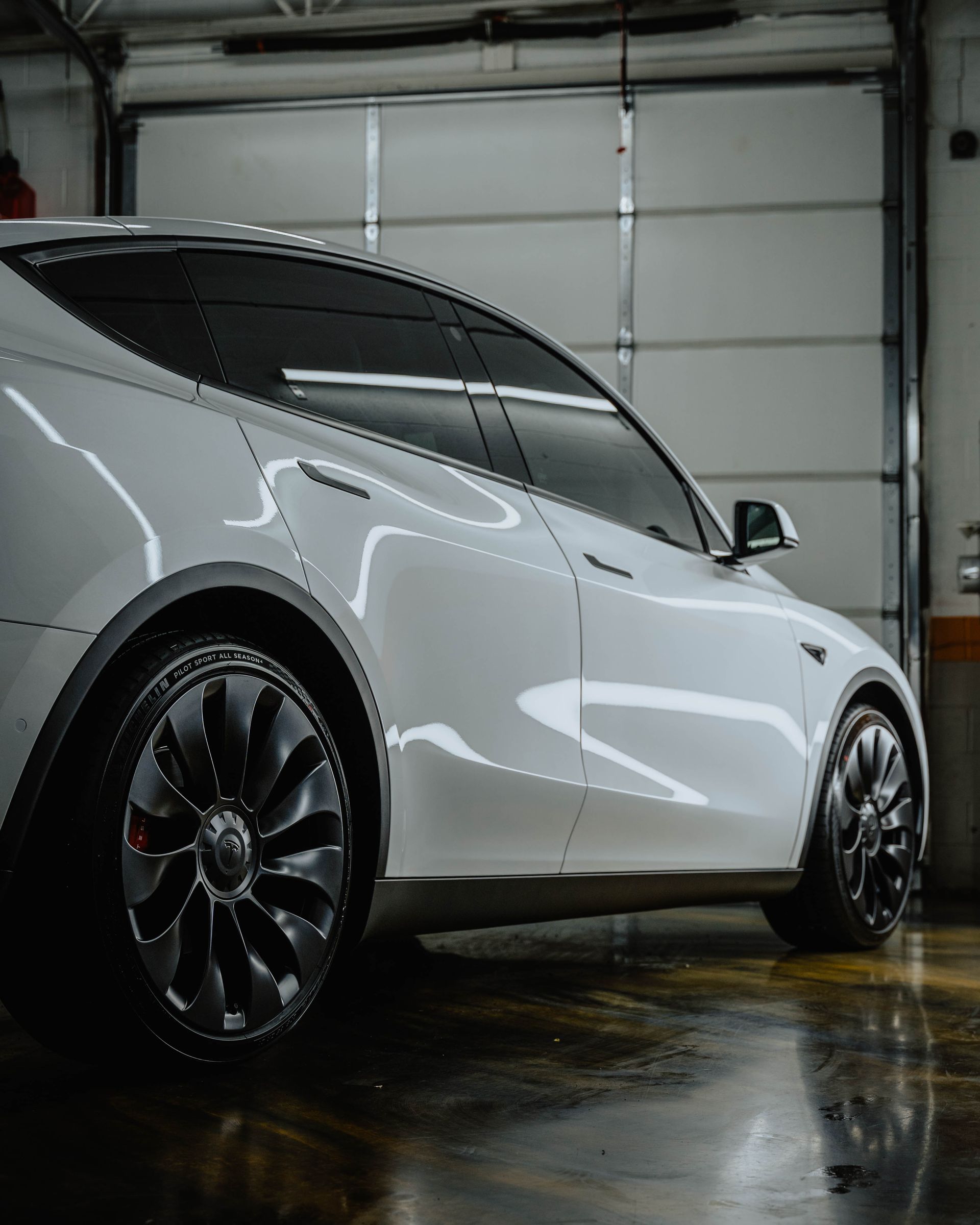 A white car is parked in a garage next to a garage door.