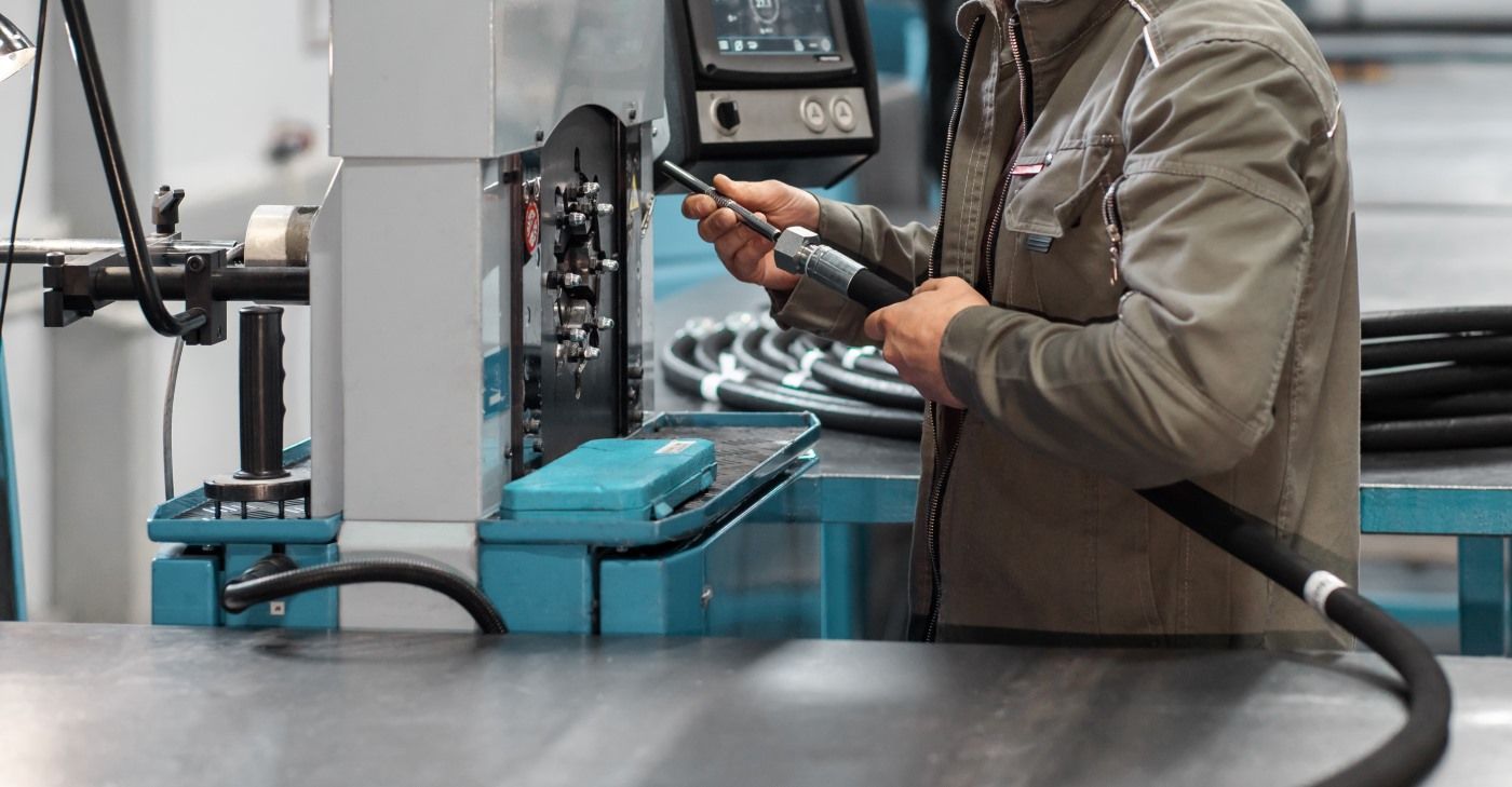 A Man Is Working On A Machine In A Factory — HI PSI Hydraulics in South West Rocks, NSW