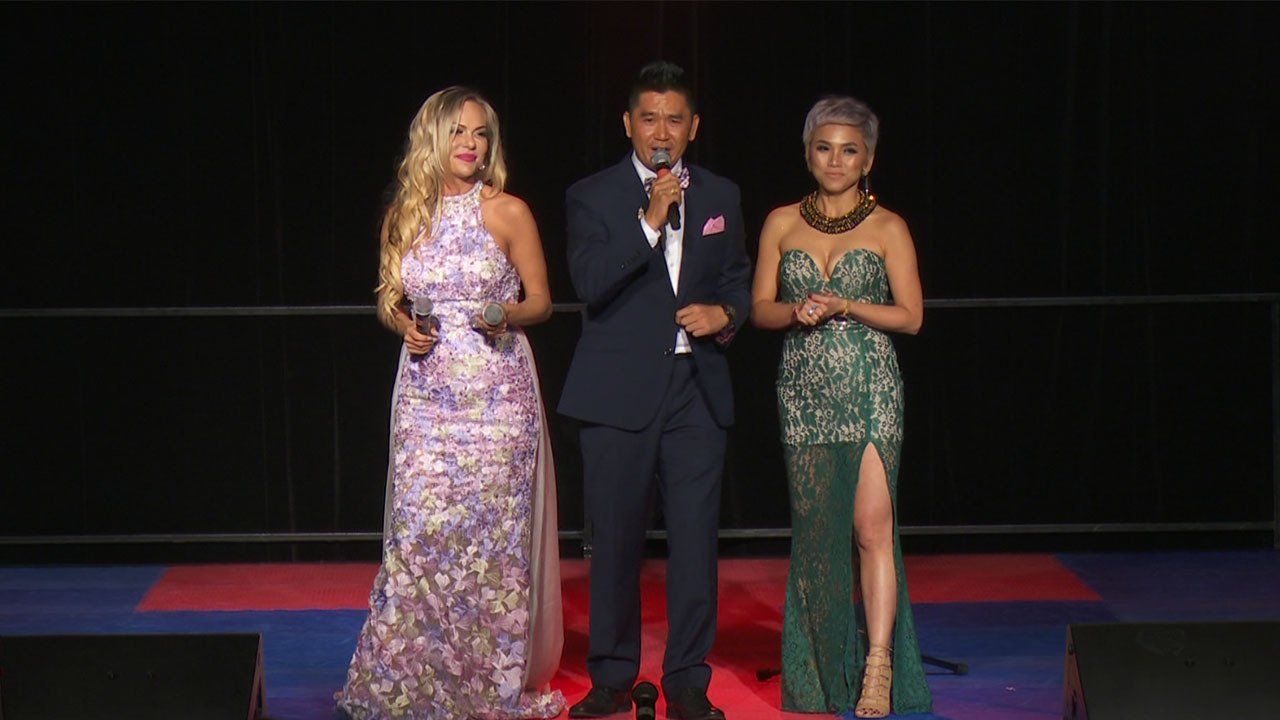 A man and two women are standing next to each other on a stage.