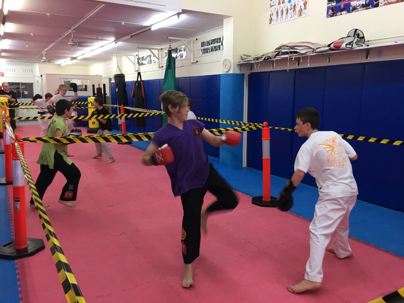 A group of kids are practicing martial arts in a gym