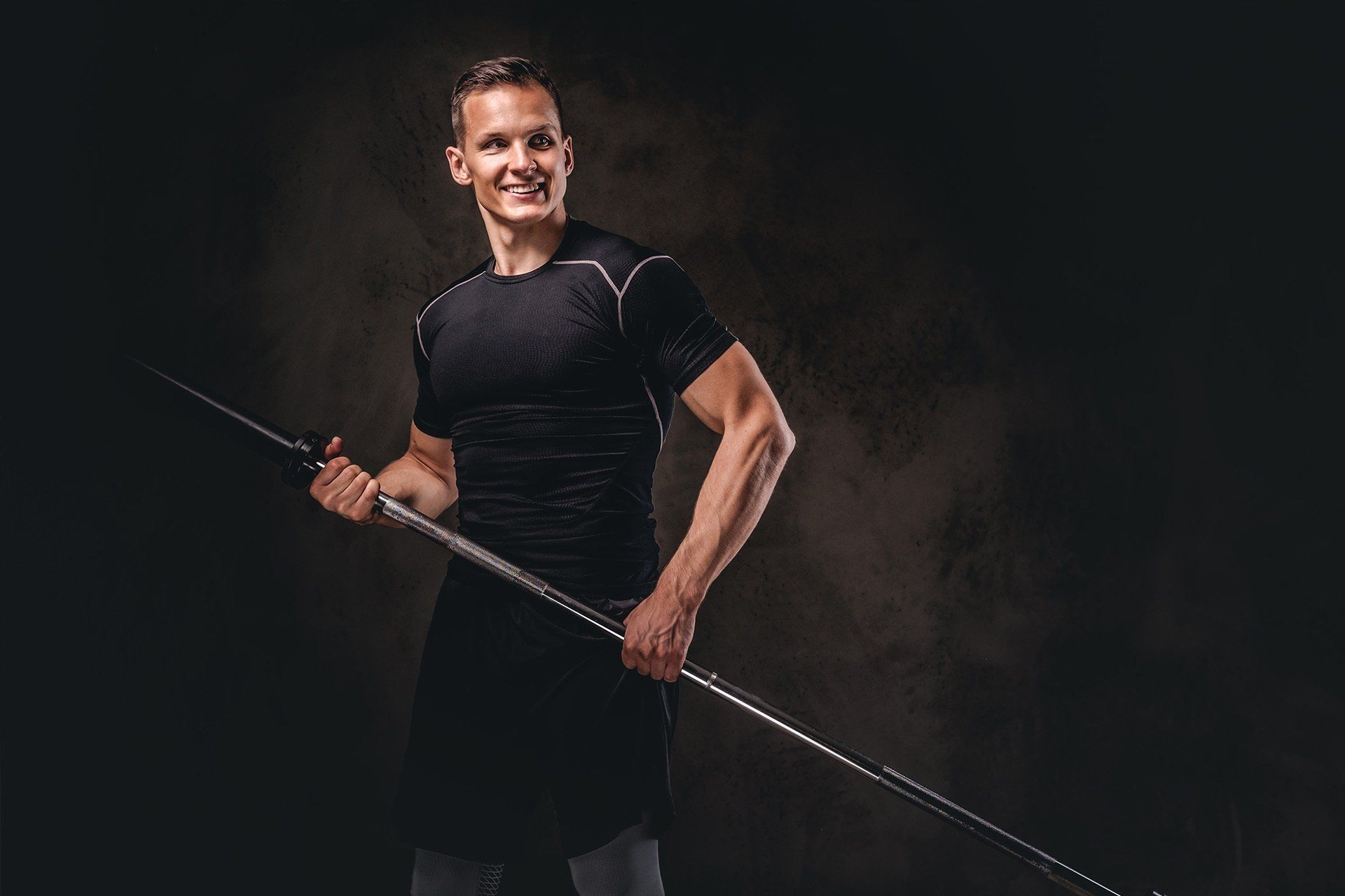 A man is holding a barbell in his hands and smiling.