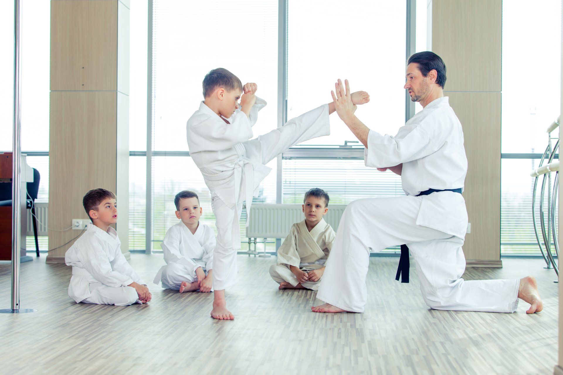 A group of young boys are practicing karate with a man in a gym.