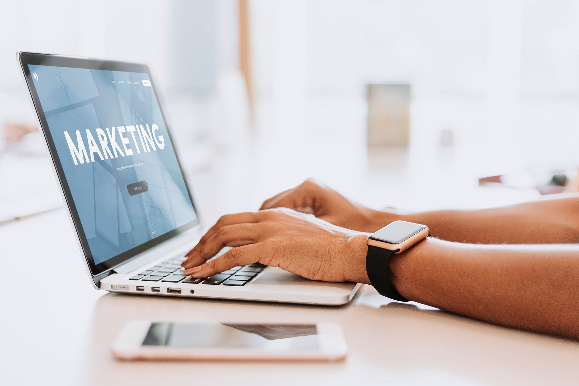 A person is typing on a laptop computer with the word marketing on the screen.
