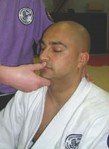 A man in a karate uniform is getting a massage from another man.