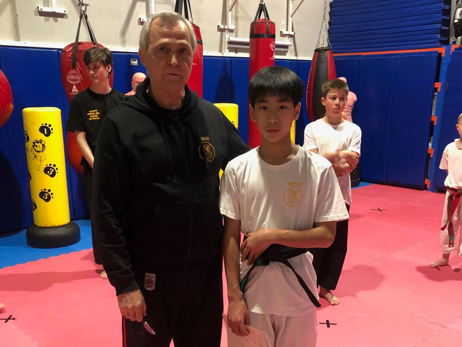 A man and a boy are standing next to each other in a gym.