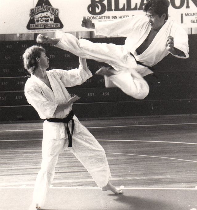 Two men practising martial arts in front of a Billabong sign