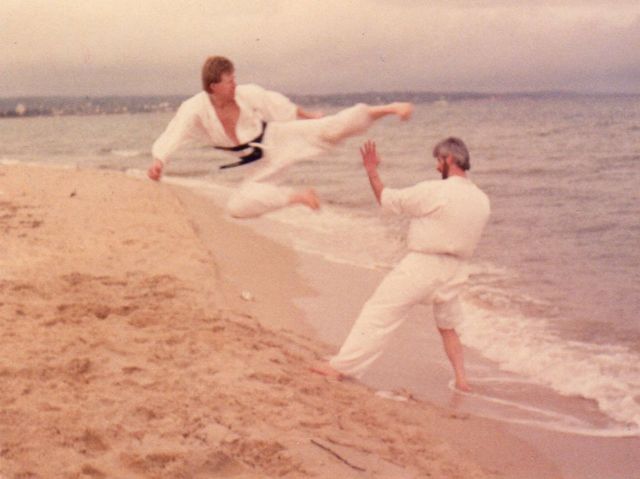Two men practising martial arts on the beach
