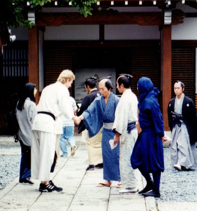 A group of people standing on a sidewalk in front of a building
