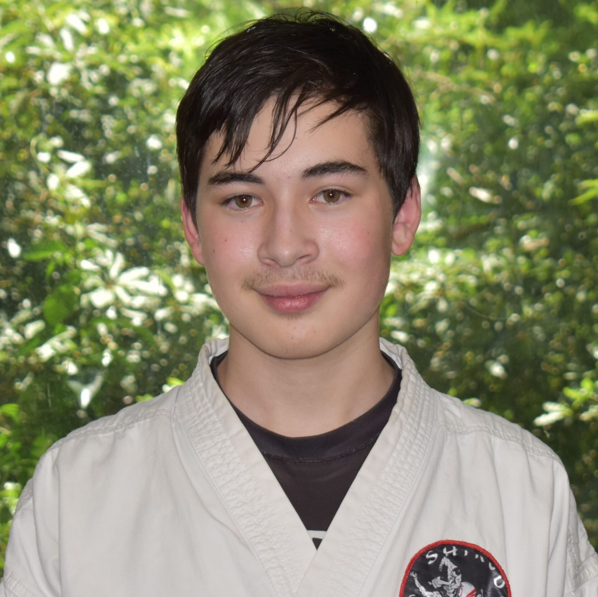 A young man wearing a white karate uniform with a black shirt underneath