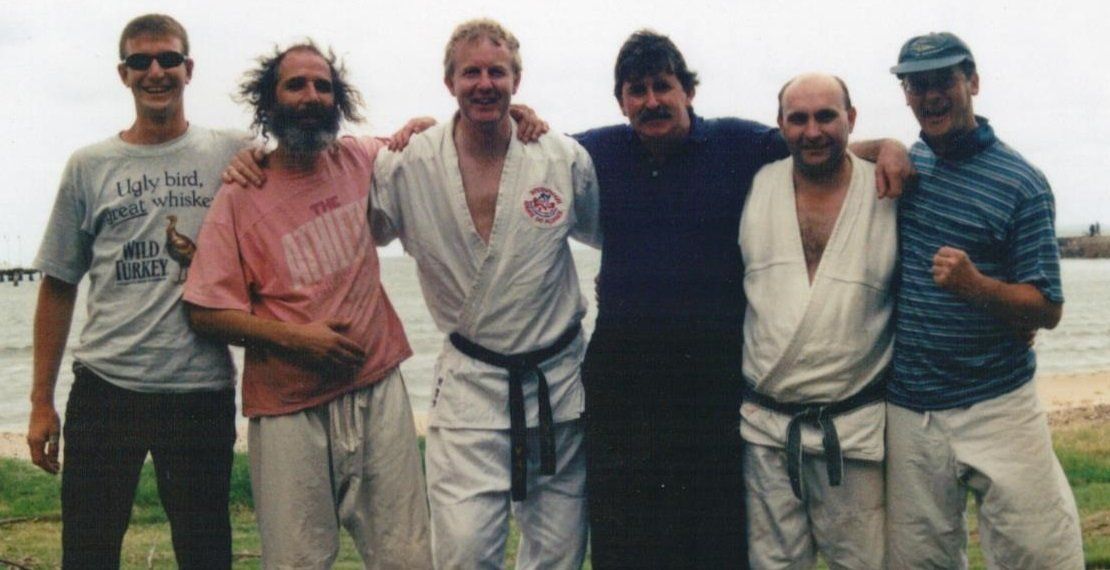 A group of men are posing for a picture and one of them is wearing a shirt that says no limit