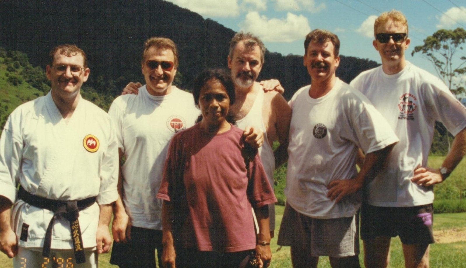 A group of men are posing for a picture with mountains in the background