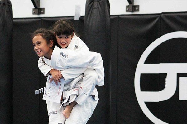 A girl is carrying another girl on her back in a gym