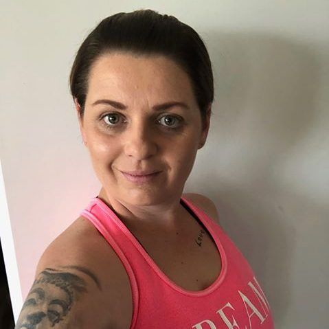 A woman wearing a pink tank top with the word dream on it