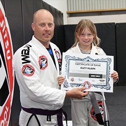 A man and a girl are holding a certificate of rank.