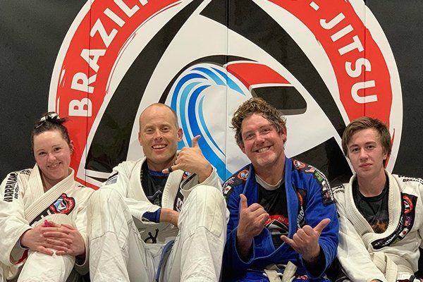 A group of people are posing for a picture in front of a brazillian jiu jitsu logo.