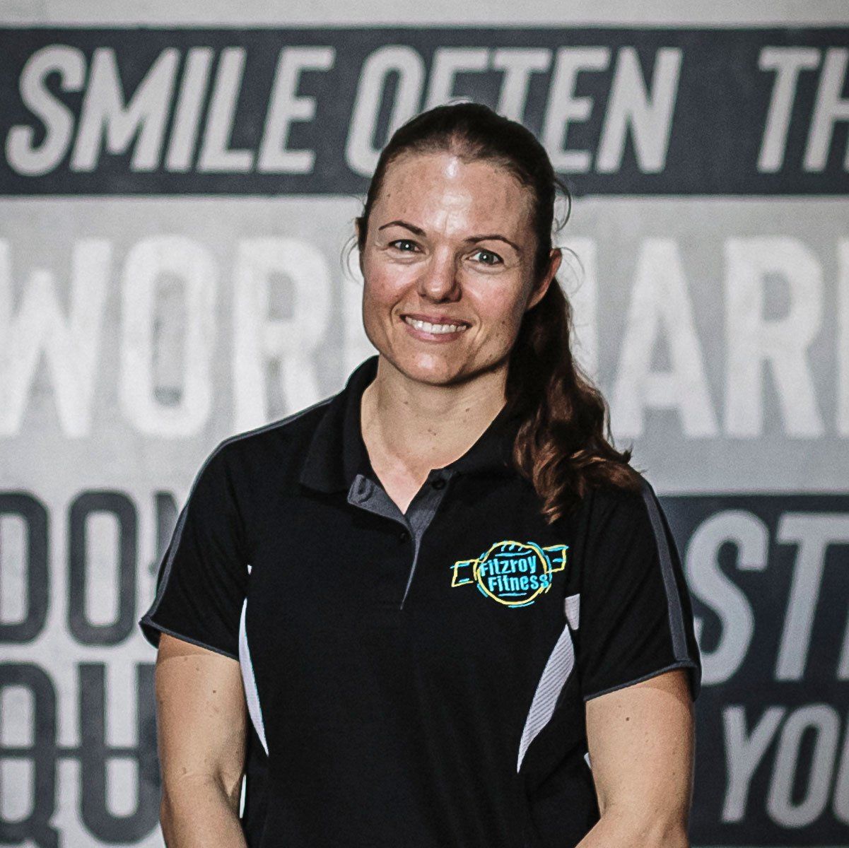 A woman is smiling in front of a sign that says smile often