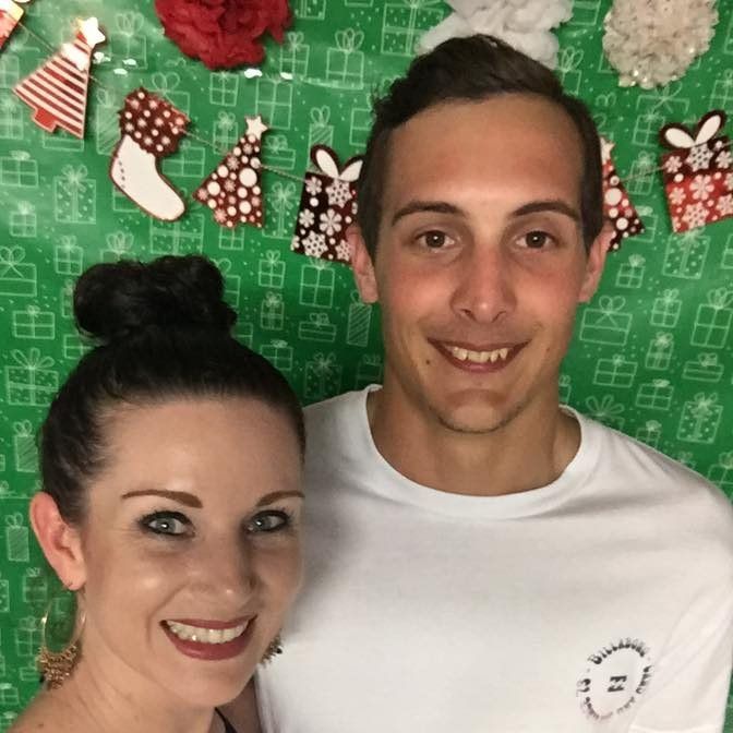 A man and a woman are posing for a picture with christmas decorations in the background