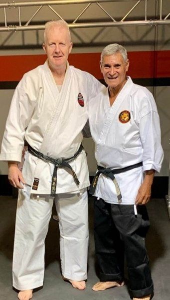Two men in karate uniforms are posing for a picture.