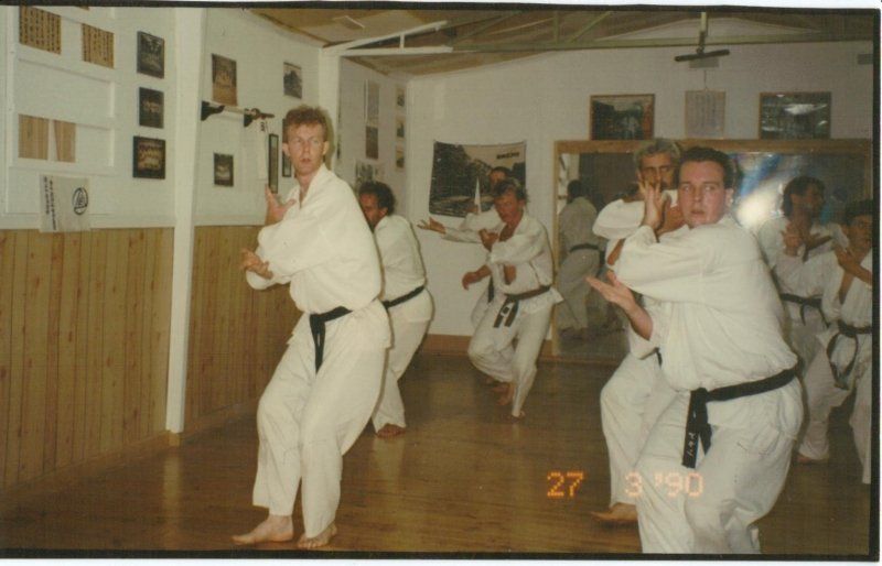 A group of men in white karate uniforms are practicing karate
