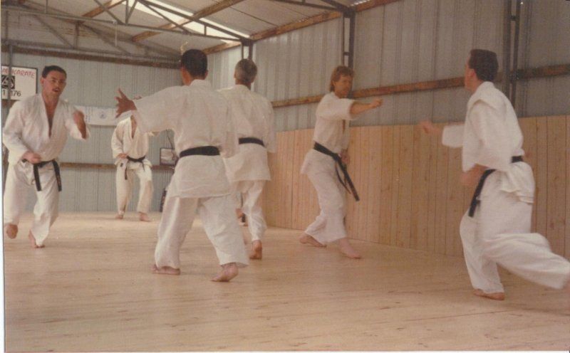 A group of people are practicing karate in a gym.