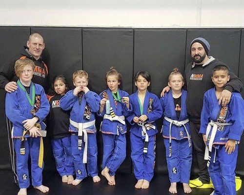 A group of children in blue karate uniforms are posing for a picture.