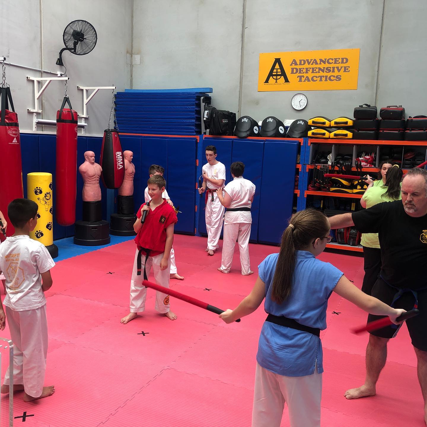 A group of people are practicing martial arts under a sign that says advanced defensive tactics