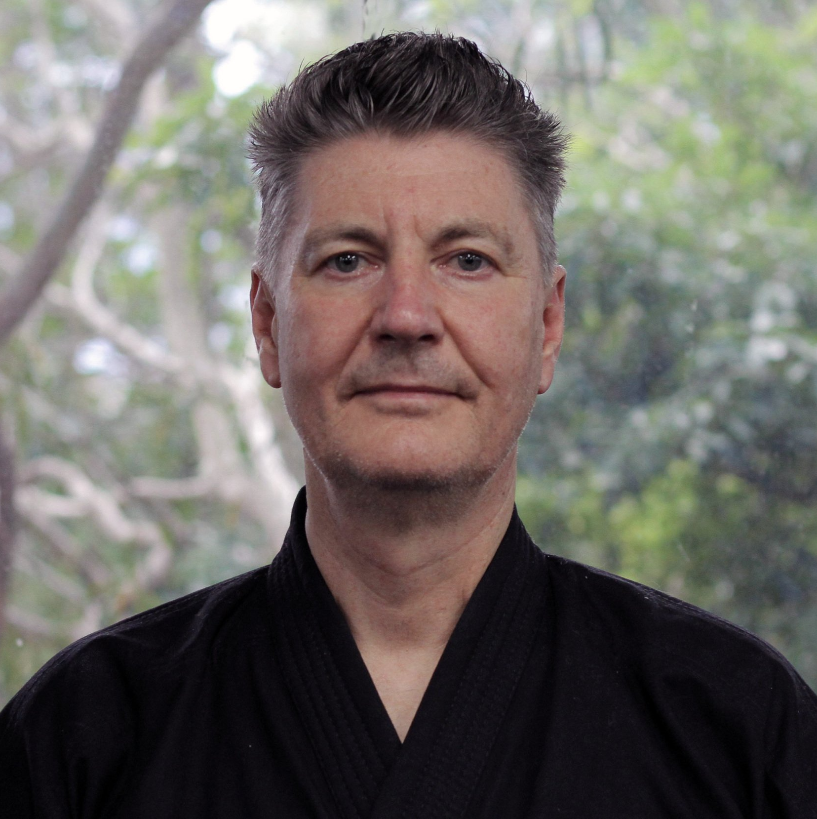 A man in a black shirt is looking at the camera.