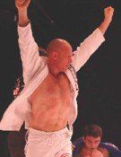A man is standing in a boxing ring with his arms in the air.