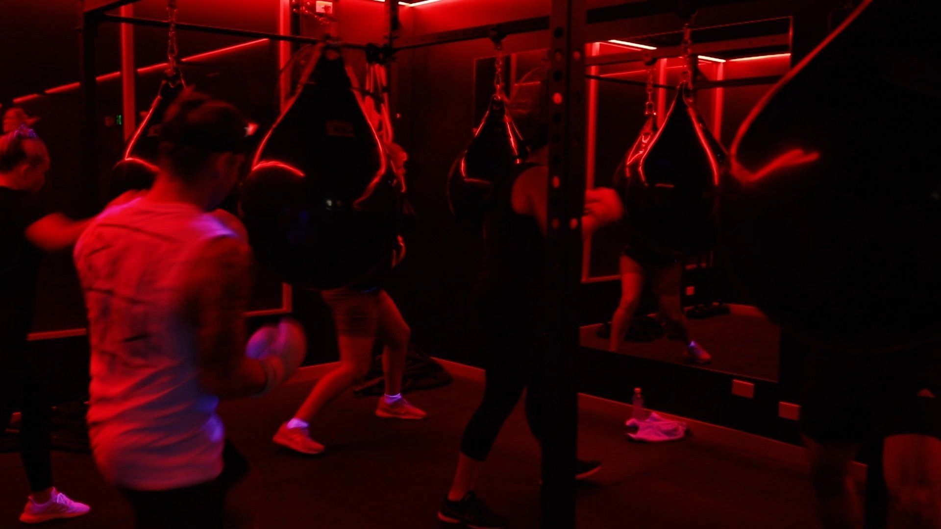 A group of people are boxing in a gym with red lights.