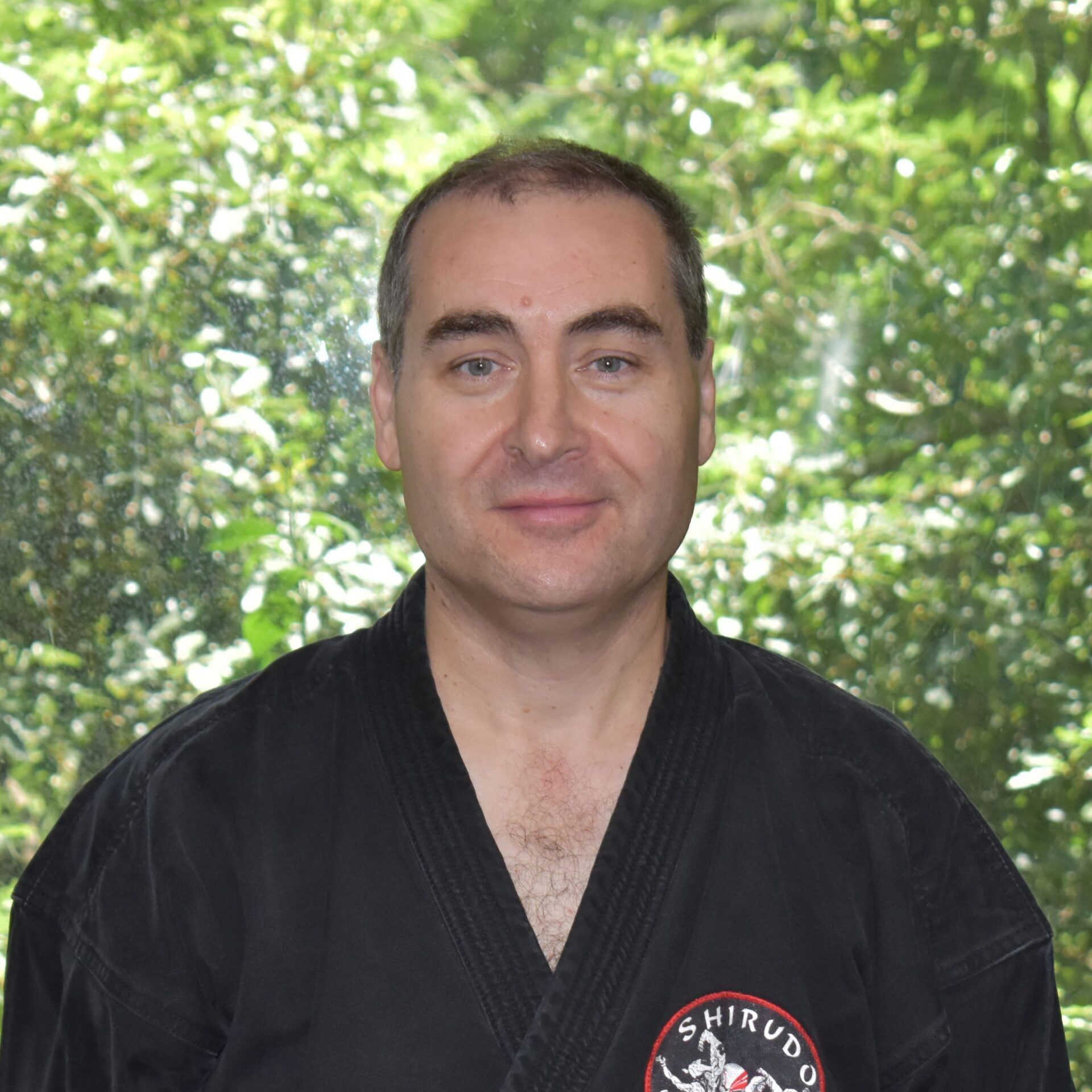 A man wearing a black karate uniform with a red emblem on his chest