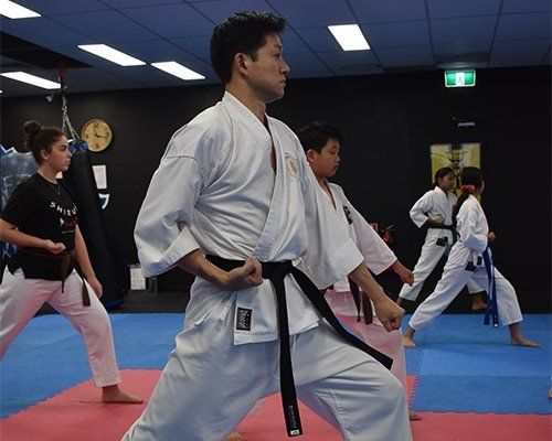 A group of people are practicing karate in a gym