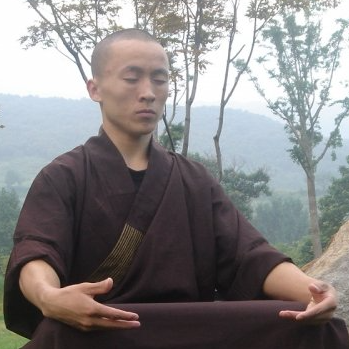 A man in a brown robe sits with his eyes closed