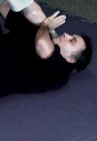 A man in a black shirt is laying on his back on a mat.