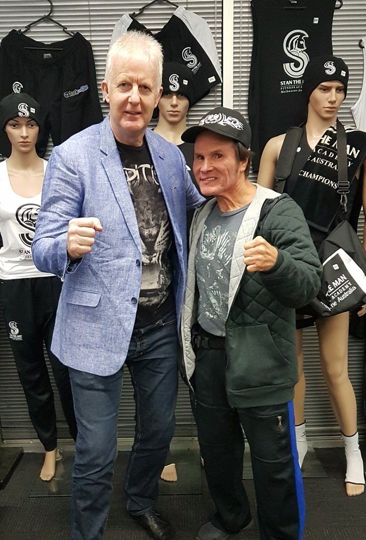 Two men are posing for a picture in front of mannequins.