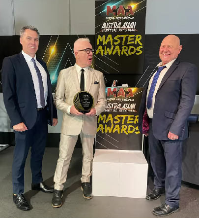 Three men in suits and ties are standing next to each other in front of a sign that says master awards.