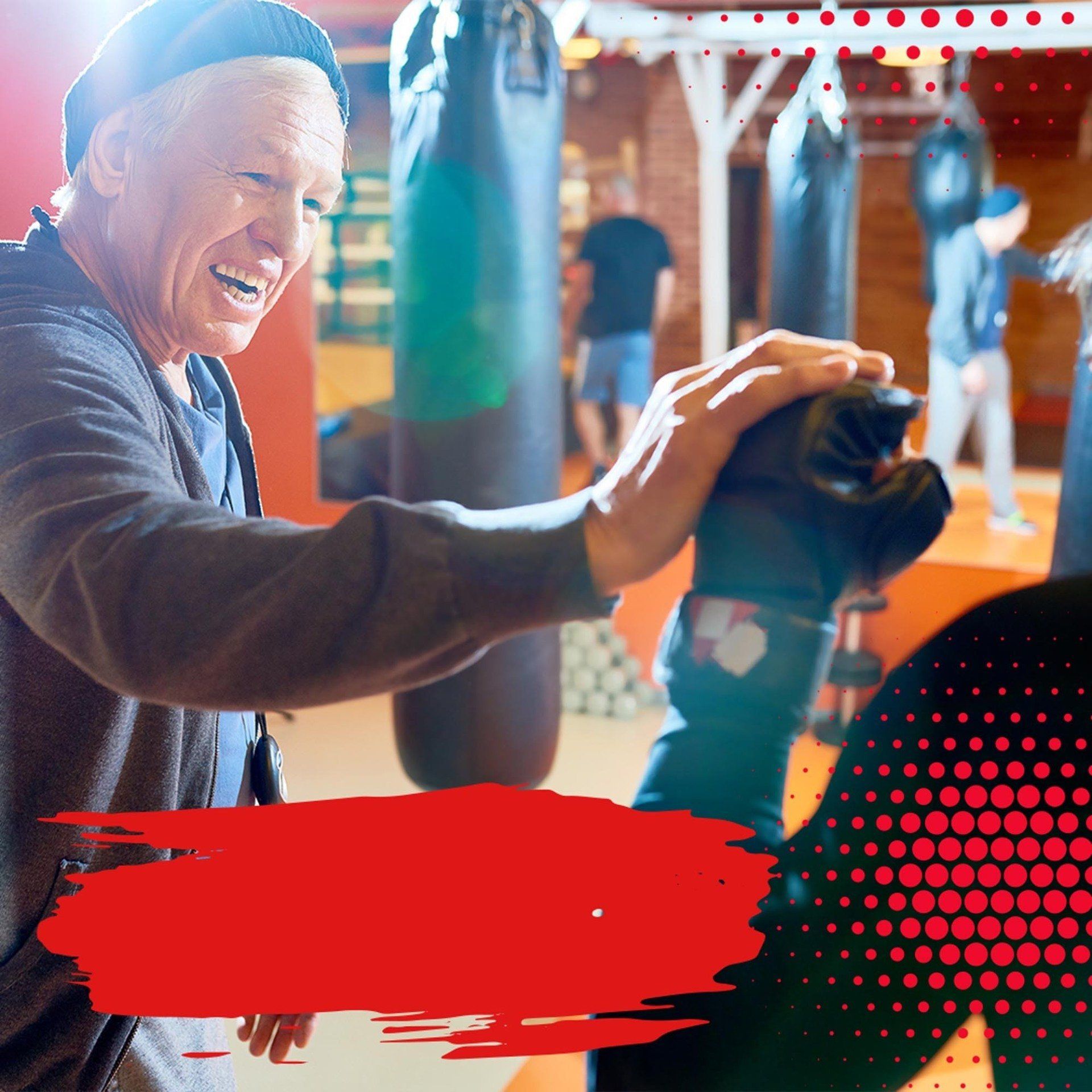 A man is holding a pair of boxing gloves in a gym.